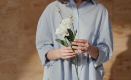 woman in white dress shirt holding white flower