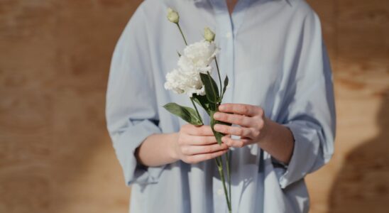 woman in white dress shirt holding white flower