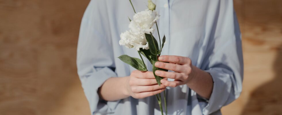 woman in white dress shirt holding white flower