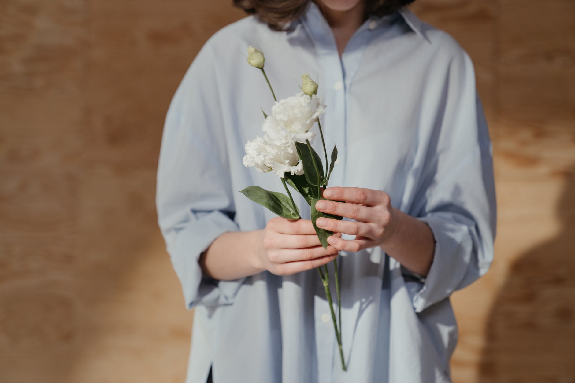 woman in white dress shirt holding white flower