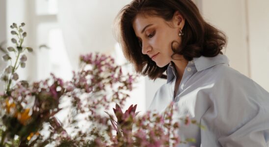 woman in white blazer looking at pink flowers