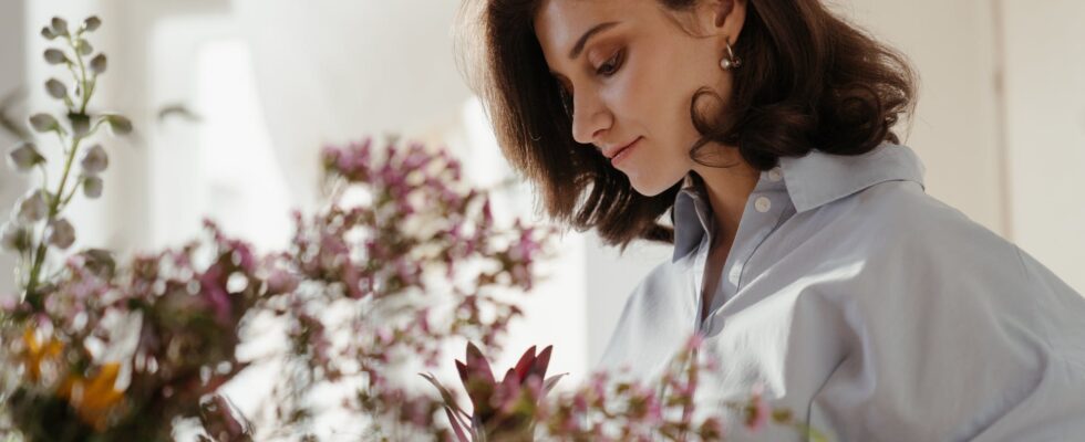 woman in white blazer looking at pink flowers