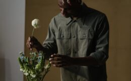 man in gray dress shirt holding white flower