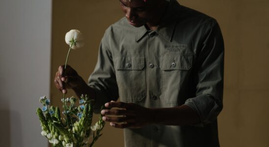 man in gray dress shirt holding white flower