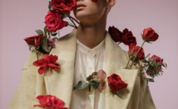 a handsome man in beige long sleeves with red roses