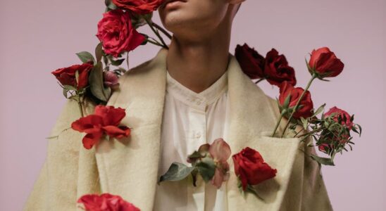 a handsome man in beige long sleeves with red roses
