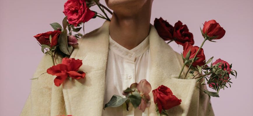 a handsome man in beige long sleeves with red roses