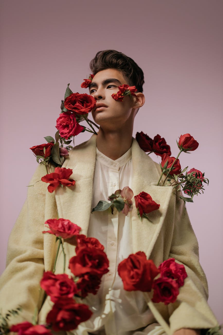 a handsome man in beige long sleeves with red roses